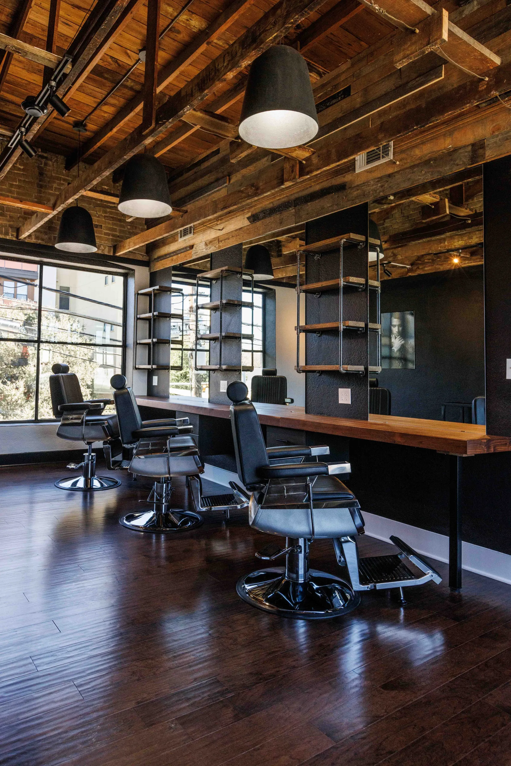 Pendant lights and a patterned ceiling above a row of barber stations
